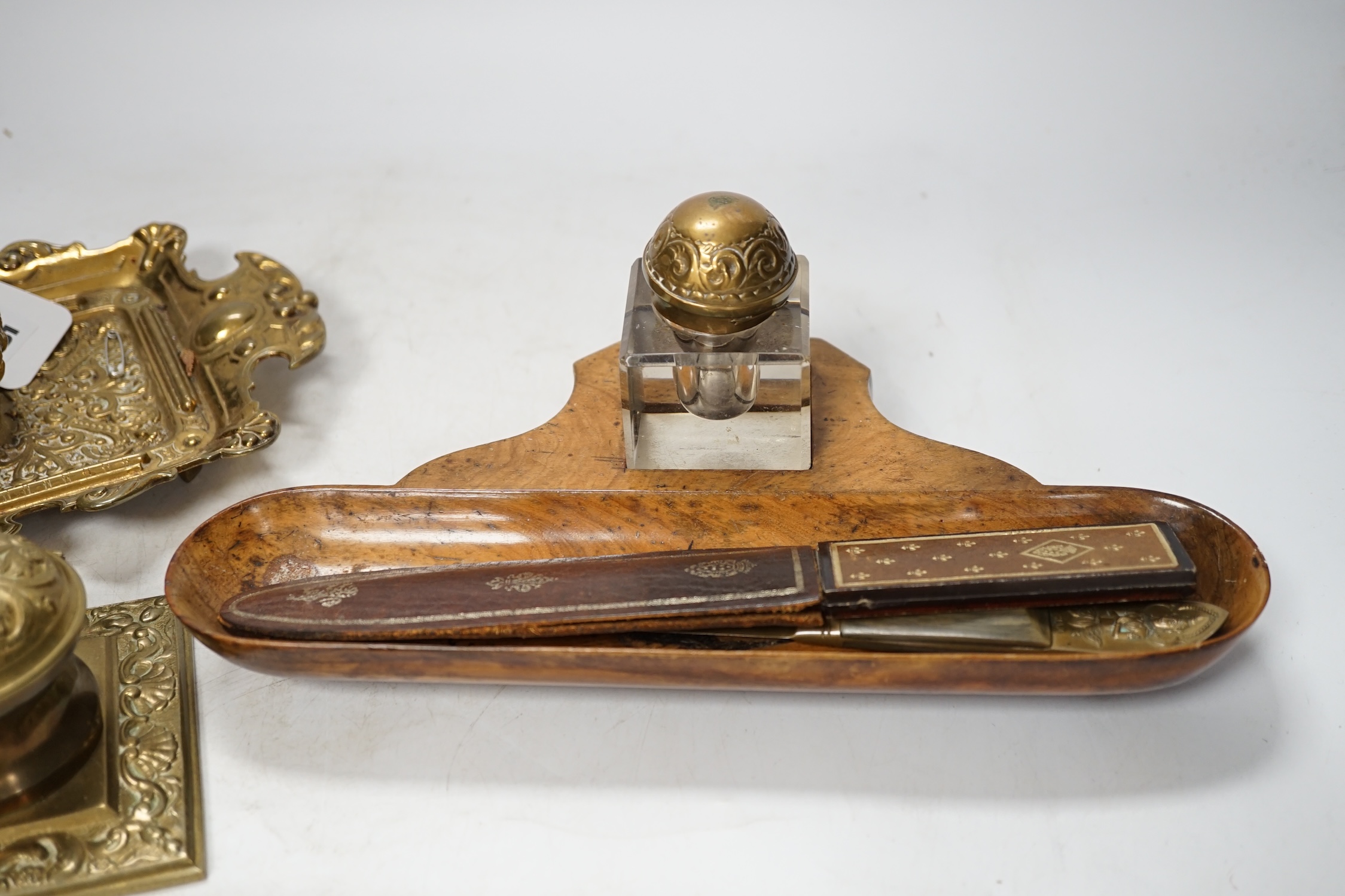 Sundry items to include brass desk stand, inkwells, letter openers and a cigar cutter, largest 26cm wide. Condition - fair